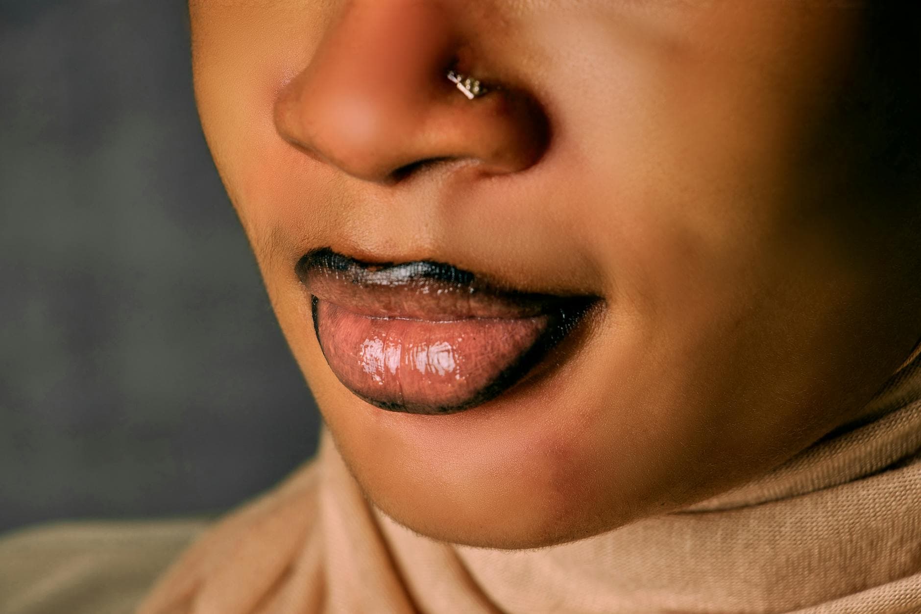 A beautiful Black woman with textured natural hair wearing a vibrant red lipstick, smiling confidently in a well-lit setting, showcasing the perfect lip color for dark skin tones.