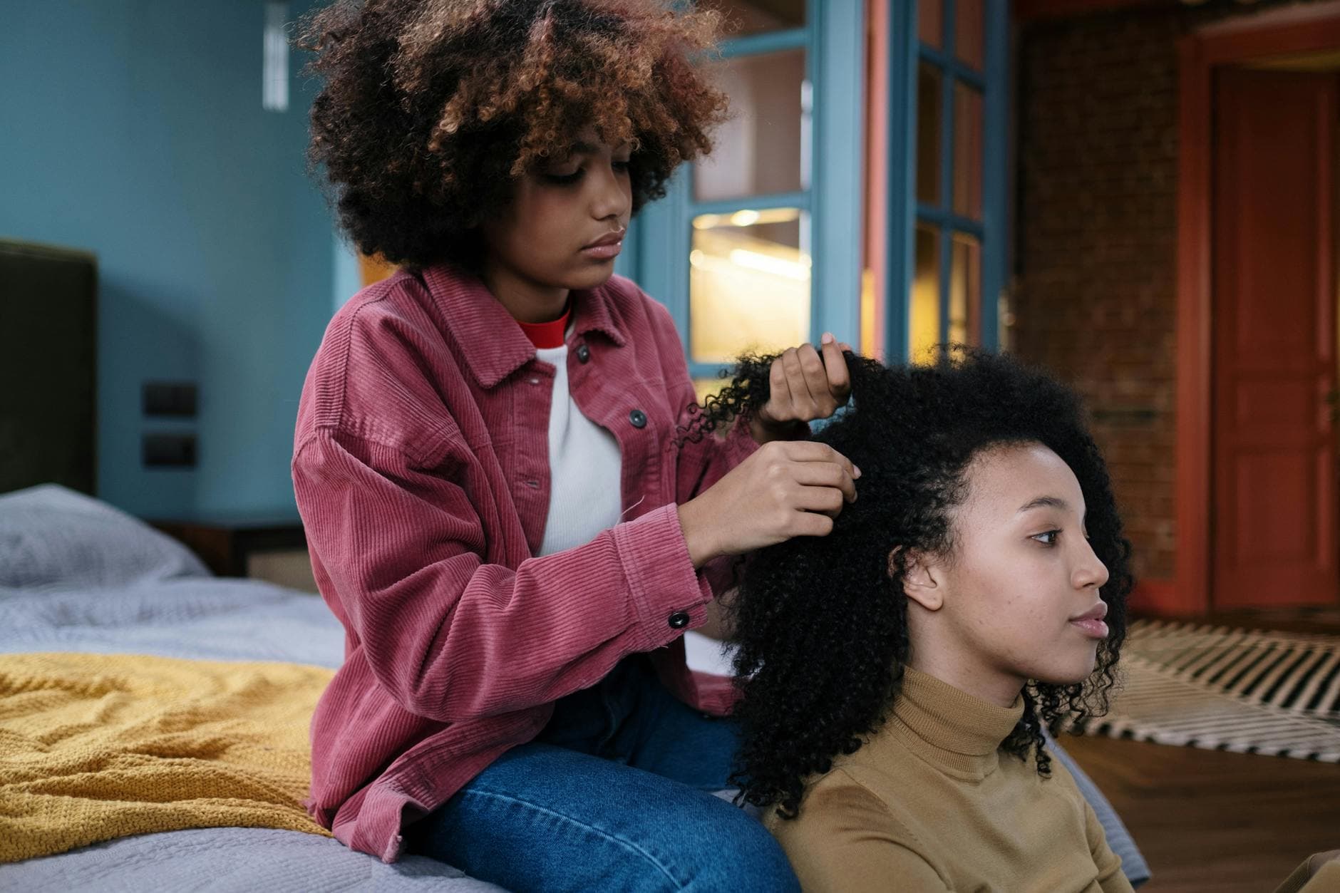 A close-up shot of a Black woman with beautifully defined curls and a braid out hairstyle, showcasing glossy, voluminous waves in a well-lit, professional setting.